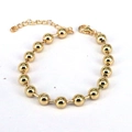 Dettaglio di un bracciale con perline dorate, chiusura a moschettone e catena regolabile - Oro
