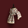 Close-up of beige knitted Christmas scarf with red festive patterns on a red background - Small Snowflake White