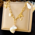 Detail van gouden zeester- en schelphangers aan een vintage bohemien ketting met zeethema - Wulpschelp en Dolfijn Stijl (N3363)