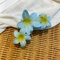 Close-up of sky blue acrylic flower hair claw clip with matte resin texture and yellow center - Blue