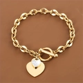 Détail d'un bracelet doré avec fermoir OT et breloques en forme de cœur en oxyde de zirconium - Doré