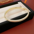 Primer plano de brazalete geométrico dorado con circonitas en estuche de joyería - Brazalete - Dorado (Estilo Circonita Completa)