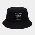 Detailed close-up of the black canvas bucket hat with white 80th birthday printed slogan - M (56-58cm) / 80th Birthday Theme (Black 80) / Black