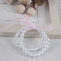Close-up of double-layered white imitation pearl bracelet with a pink ribbon bow - Double Layer 6MM+8MM White Pearl With Pink Ribbon Bracelet