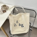 Detail of off-white canvas tote bag featuring front pocket and blue a hag letter print - Off-white