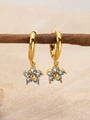 Gold hoop earrings with a light blue zircon flower pendant on a natural sandy background - March Light Blue (Aquamarine Color)