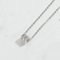 Dettaglio macro di una collana con ciondolo a cilindro argento e zirconi scintillanti - Zircone Quadrato (Argento)