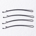 Detailed view of four black metal bobby pins with wavy design and protective round tips - Curved Style / 50 Pieces / 5.0cm / Black