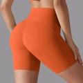 Detail view of high waisted orange yoga shorts featuring seamless butt lifting stitching - Orange
