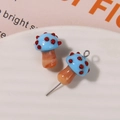 Macro shot of two glass mushroom beads for DIY jewelry with colorful polka dot caps - No.14 (Blue Cap Red Dot Orange/Brown Stem)