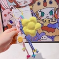 Détail d'un porte-clés tressé coloré avec une grande fleur jaune et un petit smiley blanc - 43.A08 Grande Fleur Jaune