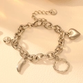 Detalle de pulsera de acero plateado con dijes de corazón y colgantes de cristal - Plateado