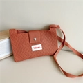 Detail of terracotta knitted crossbody bag with textured diamond pattern and logo label - Orange Red
