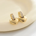 Detailed view of gold heart earrings with zircon-encrusted hoops and hollow side patterns - Gold Polished