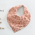 Detail of pink leopard print cotton muslin baby bib with snap closure on white background - Triangle / Cherry Pink
