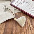 Close-up of embroidered triangle sachet with colorful braided cord on a wooden table - Apricot Puff Flower