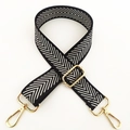 Close-up of adjustable black and white herringbone bag strap with gold metal hardware - Silver Line Arrow