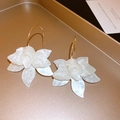 Detail of white resin flower earrings with gold hooks on a textured jewelry tray - White