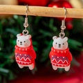 Gros plan de jolies boucles d'oreilles ours polaire de Noël suspendues à une branche - Ours polaire en pull