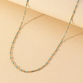 Close-up of golden necklace featuring small turquoise enamel beads on a thin chain - Gold Chain Blue Enamel Beads