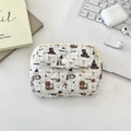 Detailed close-up of a quilted teddy bear card pouch on a desk with tech accessories - Skating Dog