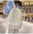 Détail du sac à dos en toile fleurie porté par un mannequin dans une bibliothèque tamisée - Tulipe Blanc Cassé