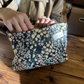 Black canvas cosmetic bag with floral embroidery and white logo label in use - Black with Yellow Ditsy Floral