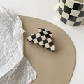 Detailopname van een zwart-witte schaakbord haarklem op een lederen mat met decoratieve items - Kleine onregelmatige klem