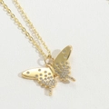 Macro-opname van gouden vlinderhanger met zirkonia op een witte leerachtige textuur - Vlinder