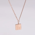 Makroansicht der Roségold-Edelstahlkette mit geometrischem quadratischem Musteranhänger - Roségold