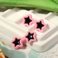 Close-up of pink star-shaped stud earrings for dolls on a white grid display tray - Pink