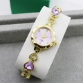 Macro shot of gold-plated heart-shaped bracelet watch with pink crystals and rhinestones - Gold + Purple