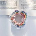 Rainbow gradient scrunchie with white polka dot mesh overlay on an open book background - Lace Rainbow