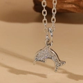 Macro shot of a silver dolphin pendant encrusted with sparkling cubic zirconia on a fine chain - Dolphin Pendant / Silver