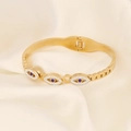 Detail eines goldenen Evil-Eye-Armbands mit blauen Steinen auf weißer Seide - Dreifacher Böser Blick Stil (10#)