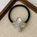 Black elastic hair tie with a silver star-shaped metal charm and irregular textured finish - Textured Clover Silver