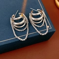 Close-up of silver multi-layer chain earrings with cubic zirconia on a blue jewelry box - Silver