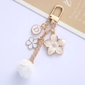 Portachiavi chic a fiori con ciondolo lettera D dorato e pompon bianco morbido - Bianco