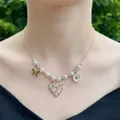 Handgemaakte parelketting met 18K gouden hart en strik hangers gedragen door model - Stijl 2 - Veelkleurige Hangers