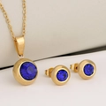 Stainless steel jewelry set with round dark blue birthstones on a white background - Gold + Blue Zirconia