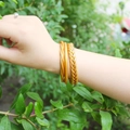 Set di tre bracciali rigidi dorati intrecciati con texture a corda sulla mano della modella - Set di bracciali rigidi intrecciati oro (30105)