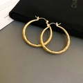 Detailansicht goldener Creolen mit gehämmerter Metalltextur auf dunklem Samtbeutel - Goldener Gehämmerter Gefalteter Creolen Stil / Gold (7# Ohrclip - Kreis)