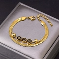 Bracelet double couche doré avec trois charms noirs présenté dans un écrin à bijoux gris - Bracelet Fleur Losange Doré
