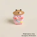 Detail view of mini resin pink pig figurine with bear hat and yellow bag accessory - Shopping Pink Pig