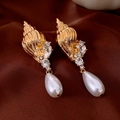 Nahaufnahme der goldenen Muschelohrringe mit Kristallen und Perlenanhängern im Retro-Stil - Goldene Schnecke Weiße Perle (Silbernadel)