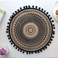 Round jute placemat with black mandala pattern and fringe tassels on a white tabletop - Type I Black Pom-poms