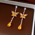 Détail de boucles d'oreilles papillon en zircon avec pierres jaunes en forme de poire - Or Jaune