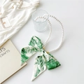 Detail of faux pearl necklace strap with green floral ribbon bow on white tabletop - Green Forest Toile
