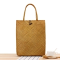 Bolso de paja natural con cierre de botón de madera y asa trenzada sobre mesa de madera - Amarillo Miel