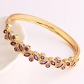 Detailed shot of gold plated bracelet with marquise-cut purple stones on a ceramic plate - Purple